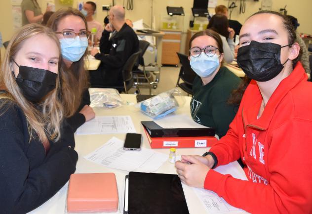 Four nursing students at a table review drug calculations